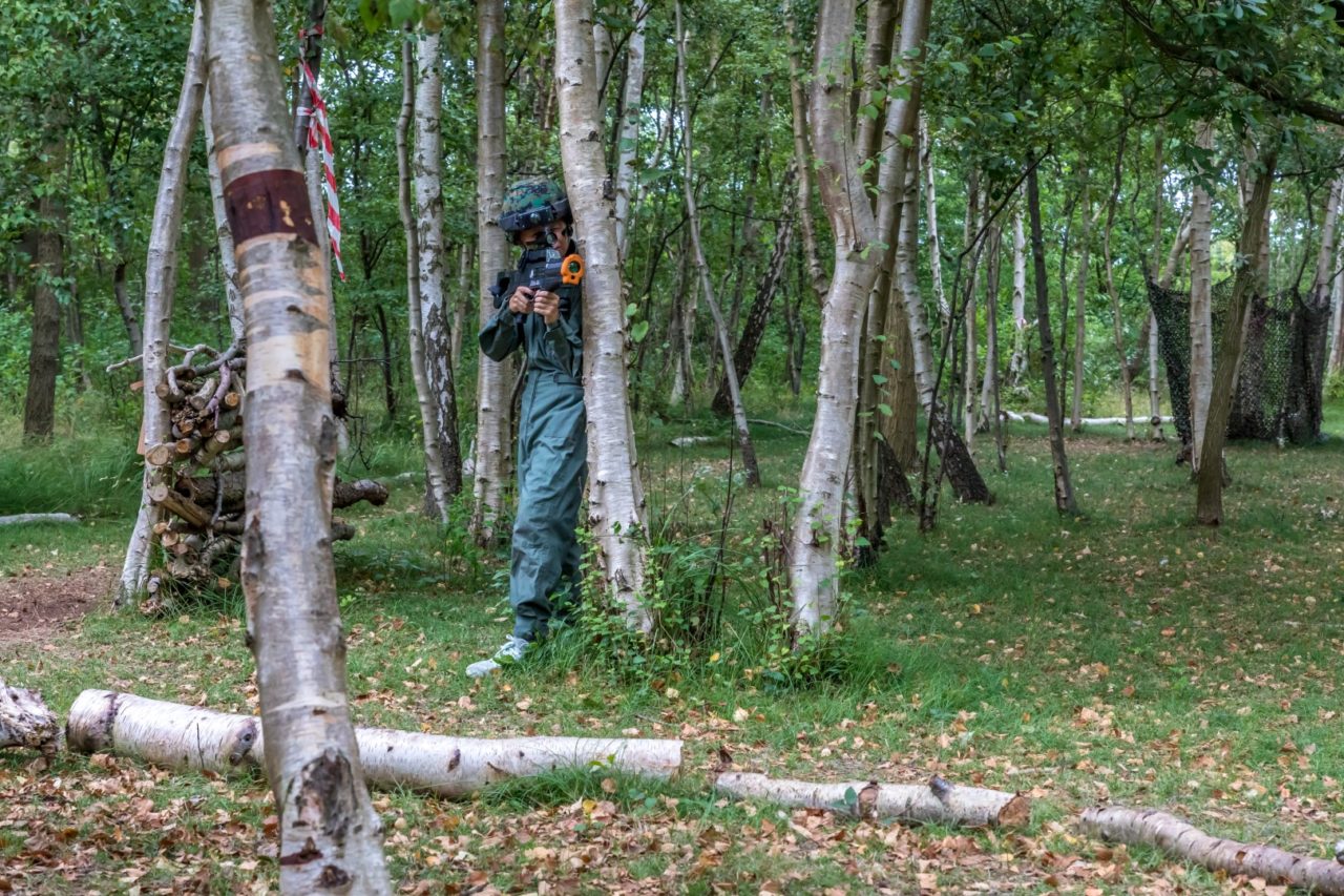 Jongen verstopt zich achter een boom tijdens een potje lasergamen